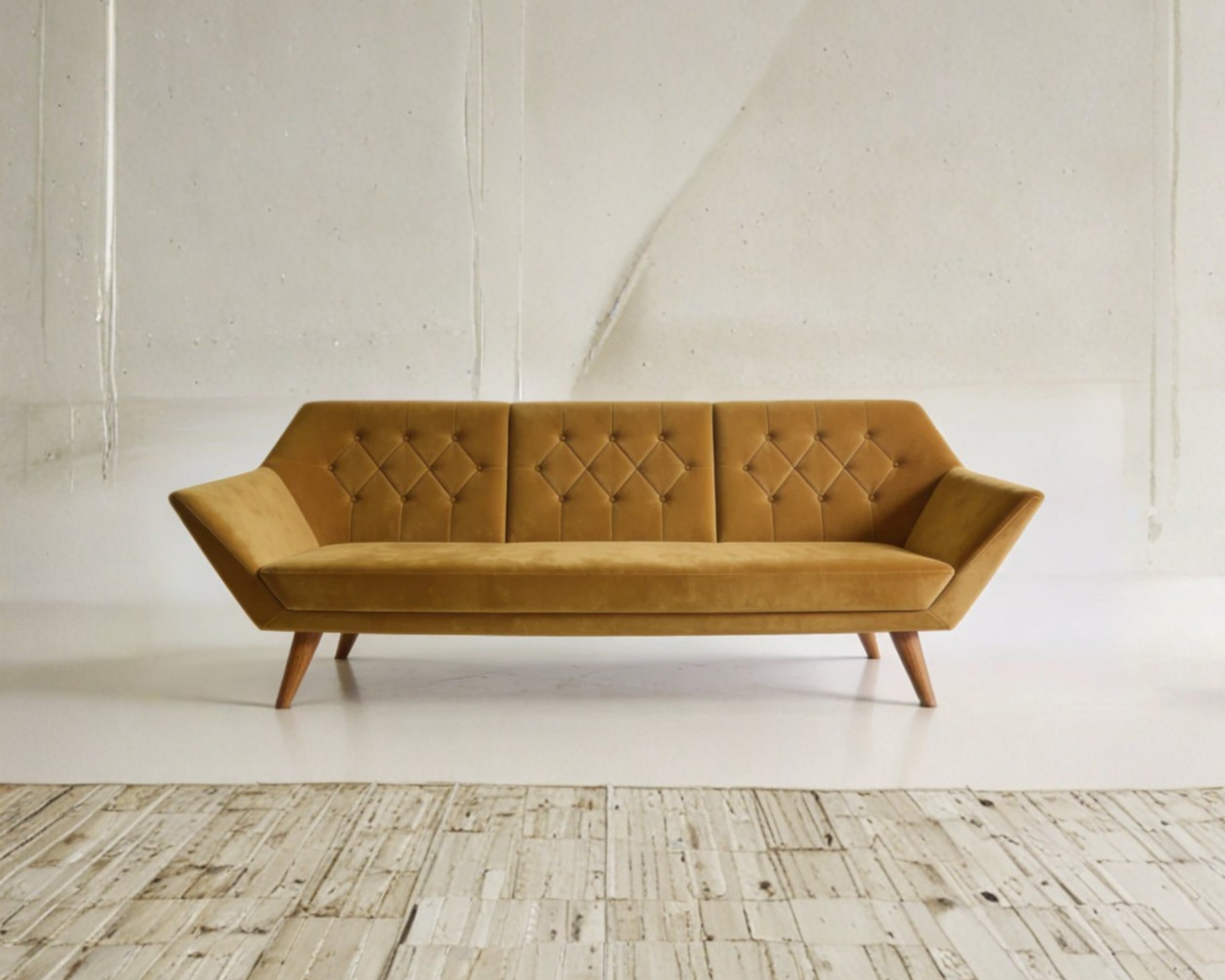 Mustard yellow sofa in a minimalistic room with wooden floor and white walls