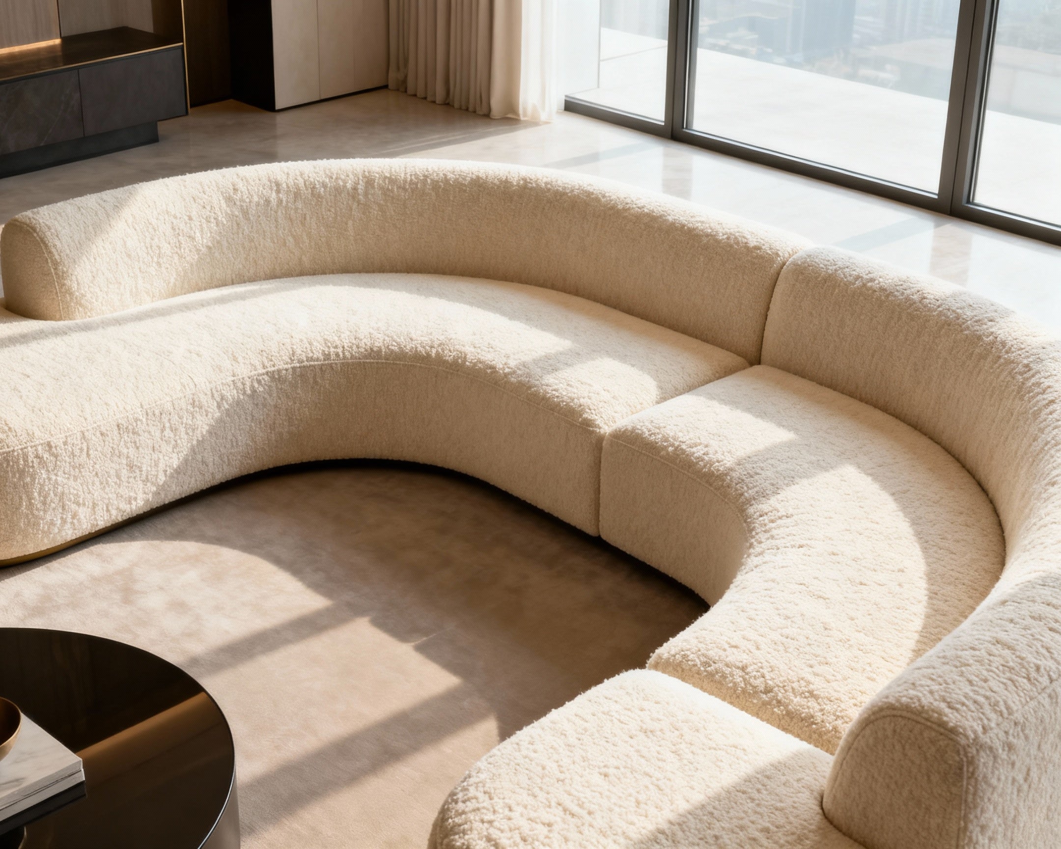 Curved beige sofa in a modern living room with large windows.